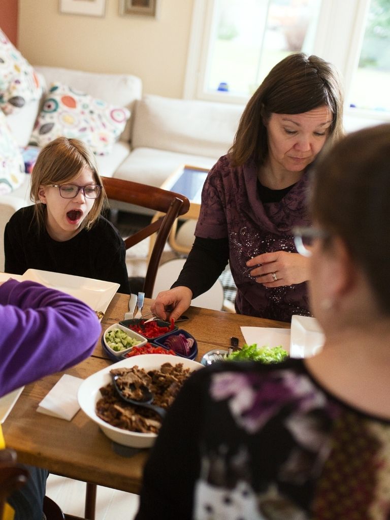 Lapsiperhe istumassa ruokapöydän ääressä syömässä.